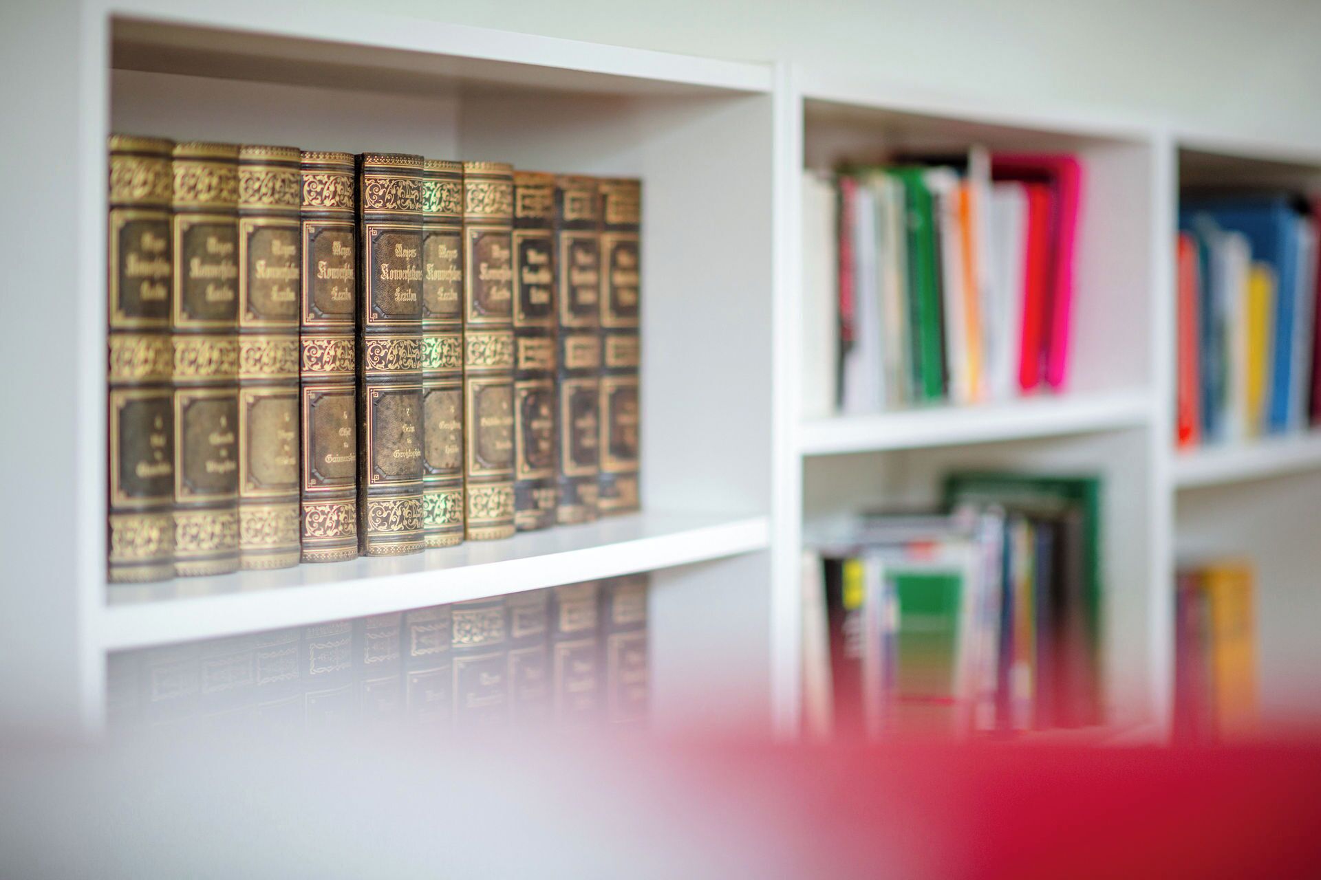A bookshelf with books and decorative boxes.