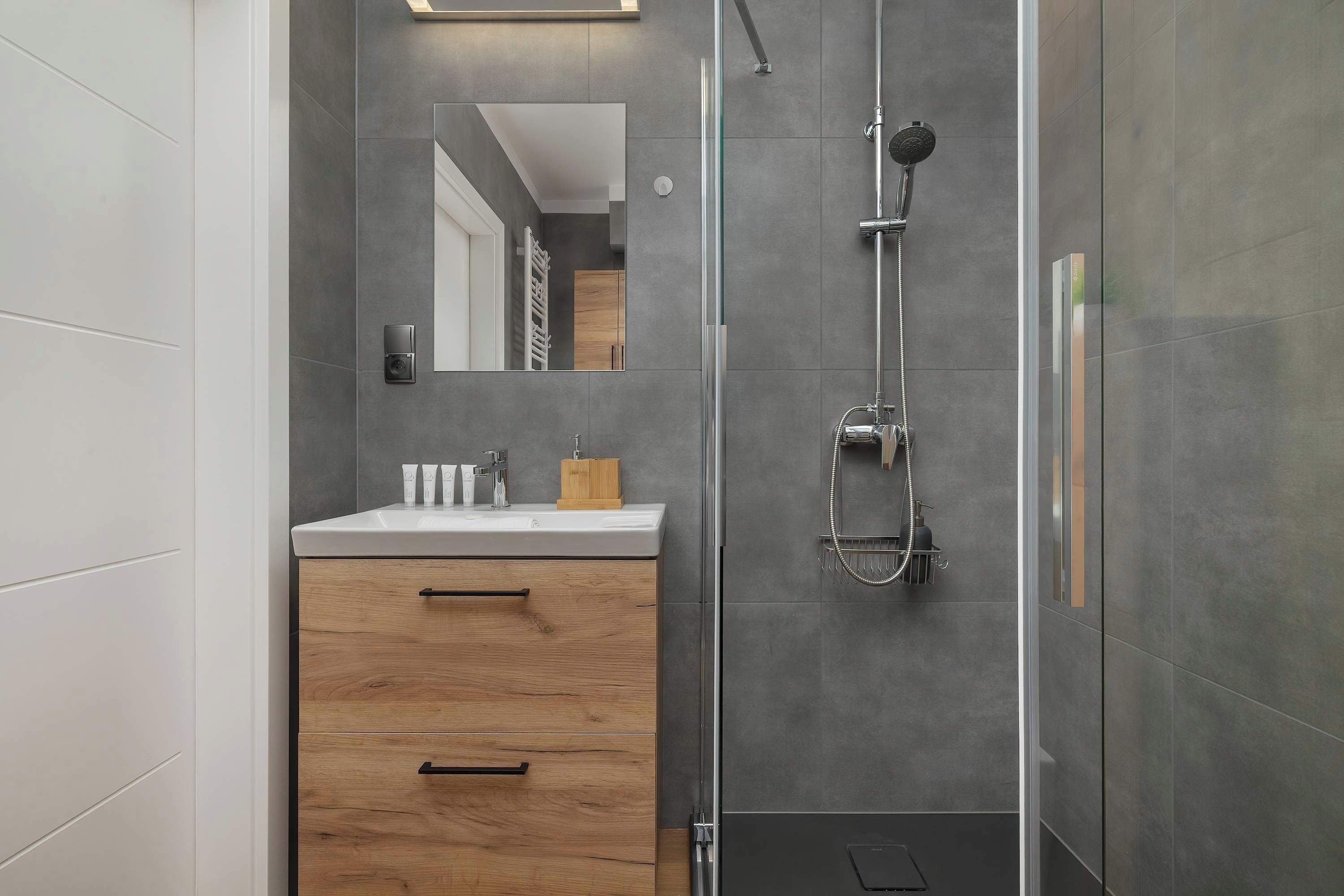 Een moderne badkamer met douche, wastafel en spiegel.