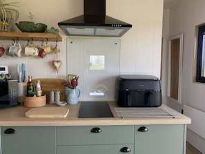 Une cuisine moderne avec une hotte noire, une machine à café et une planche à découper en bois.