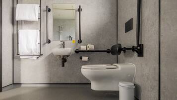 A modern bathroom with a toilet, sink, towel rack, and mirror.