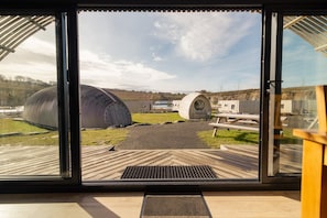 A modern building with large cylindrical structures, a wooden deck, and a clear sky.