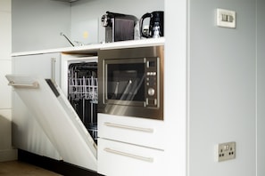 A compact kitchen with a dishwasher, oven, and a coffee maker on the countertop.