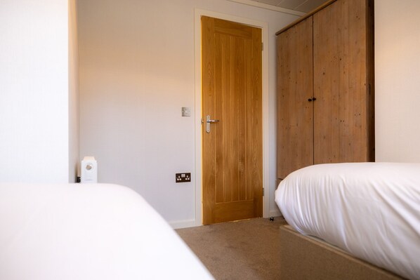 Un dormitorio con puerta de madera, una cama y una mesita de noche blanca.