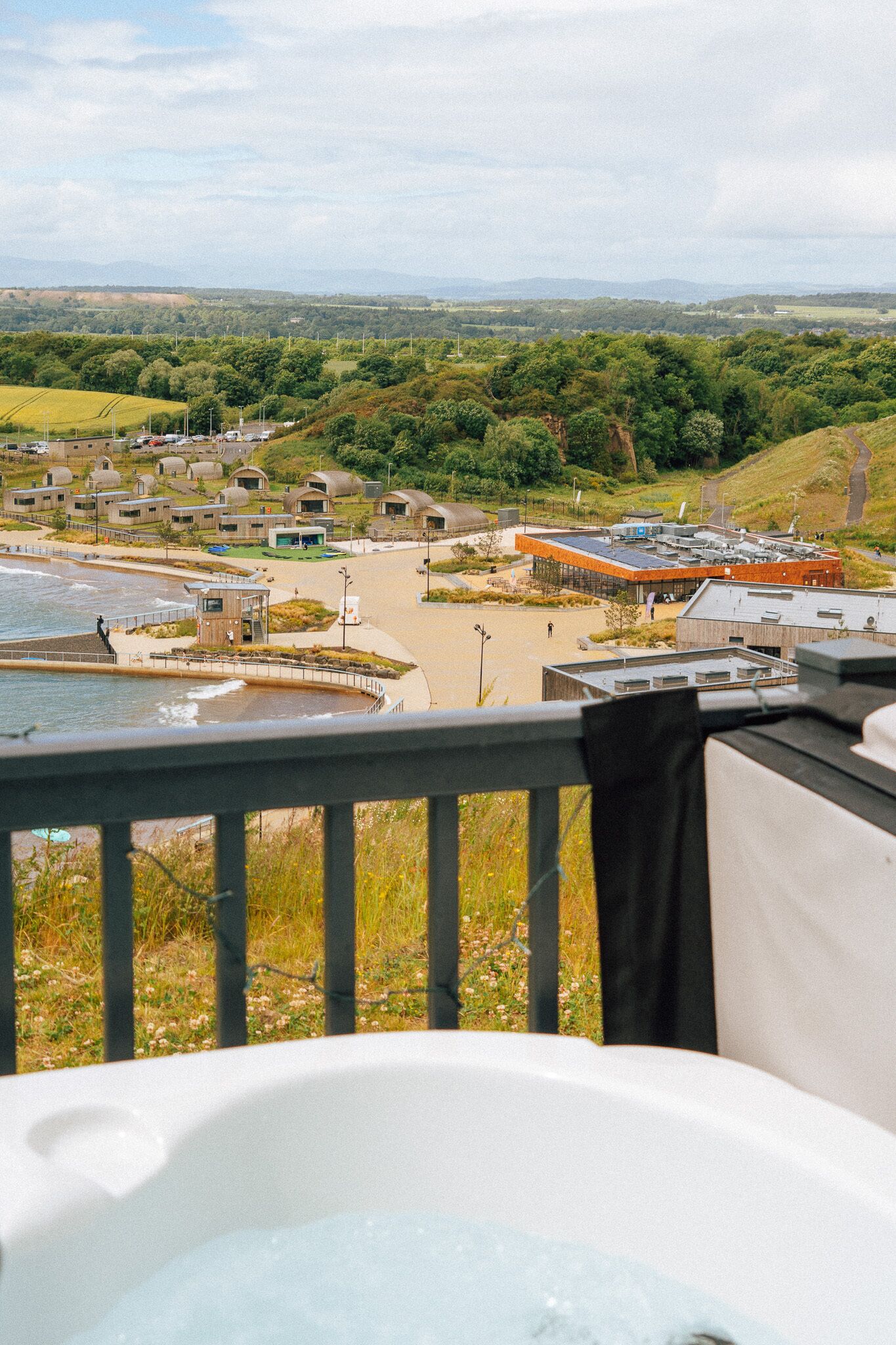 A coastal view with a beach, a pool, and a building with a modern design.