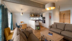 Ett modernt vardagsrum med en soffa, ett soffbord och en matplats med ett bord och stolar.