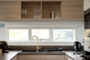 A kitchen with a window, a sink, a coffee maker, and a toaster.