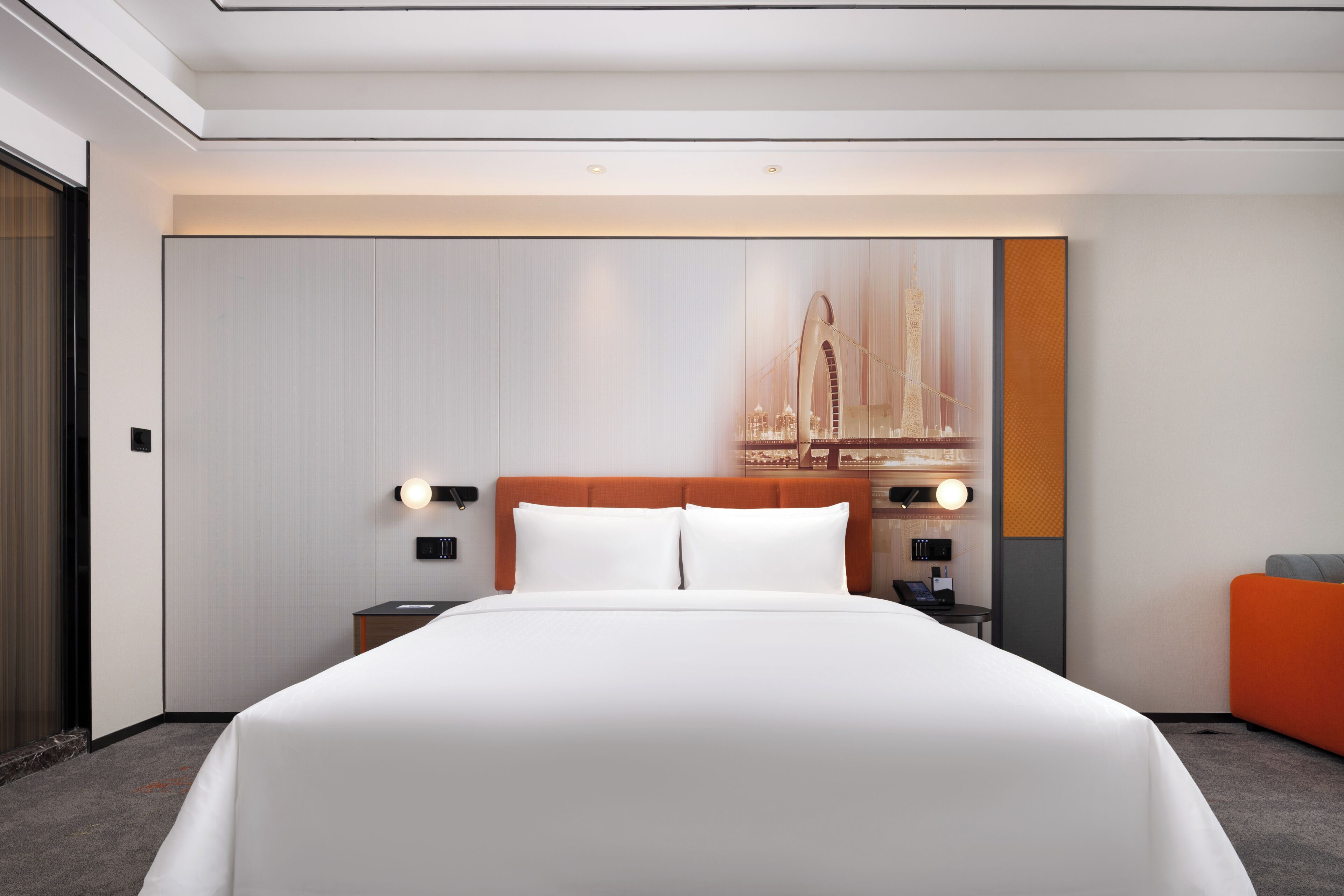 A hotel room with a large bed, a nightstand, a desk, and a chair.