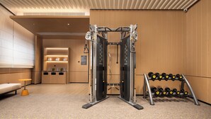 A gym with weightlifting equipment, a bench, and a rack of dumbbells.