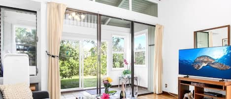 Amplia sala de estar con ventanas grandes, un televisor de pantalla plana y una mesa de centro de madera.