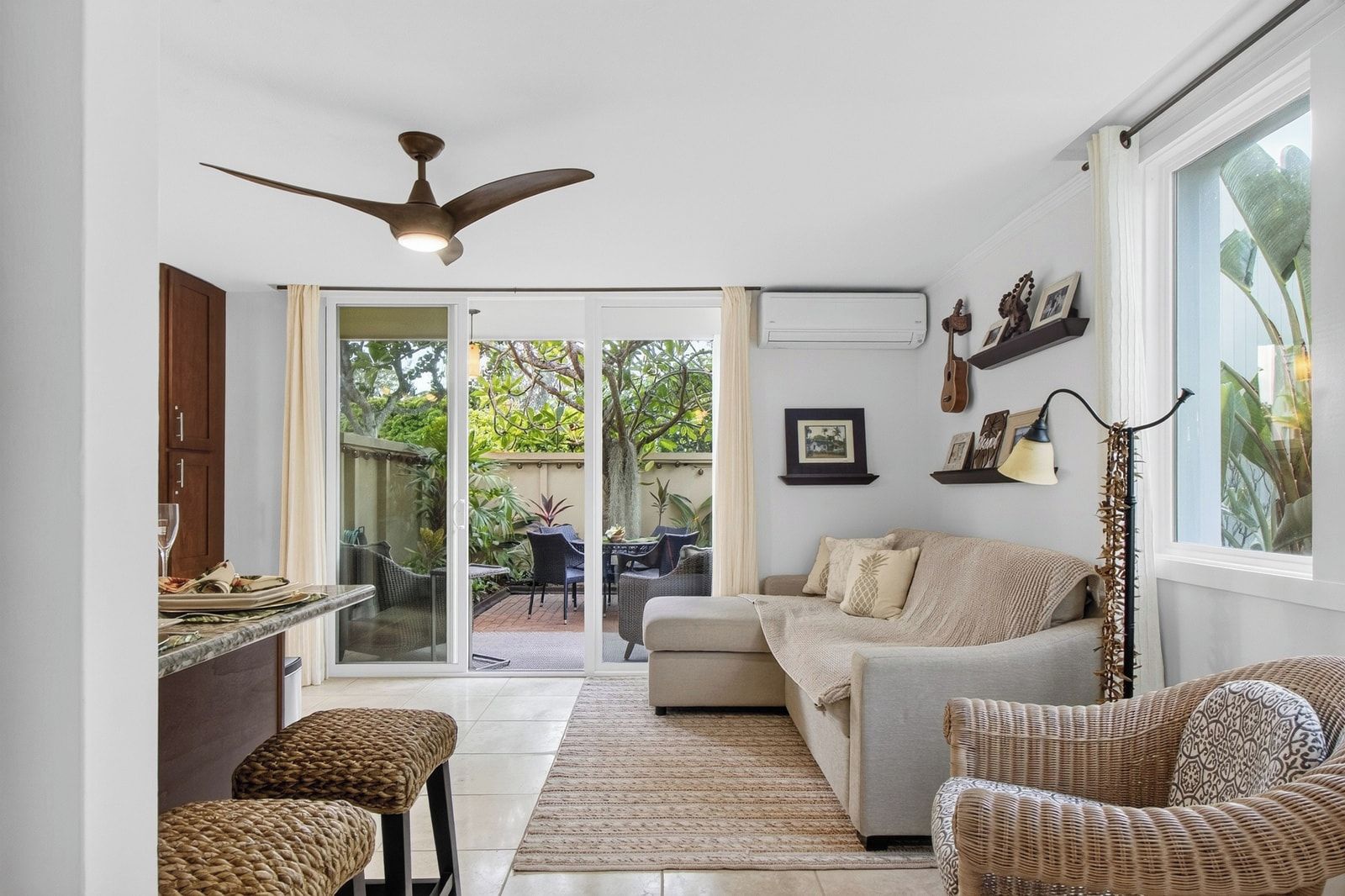 A modern living room with a sofa, a dining area, and a ceiling fan.
