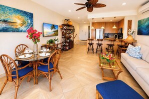 A modern living room with a dining area, kitchen, and a ceiling fan. - Napili Point | Oceanfront 2 BR, Sleeps 8 | Car Incl. w/ 6+ Nights | NAP ML-4154 KBM (Lahaina)