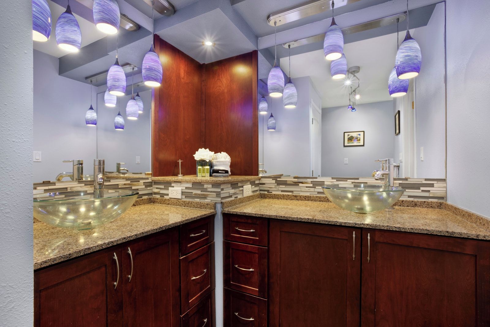 A modern bathroom with two sinks, wooden cabinets, and pendant lighting.