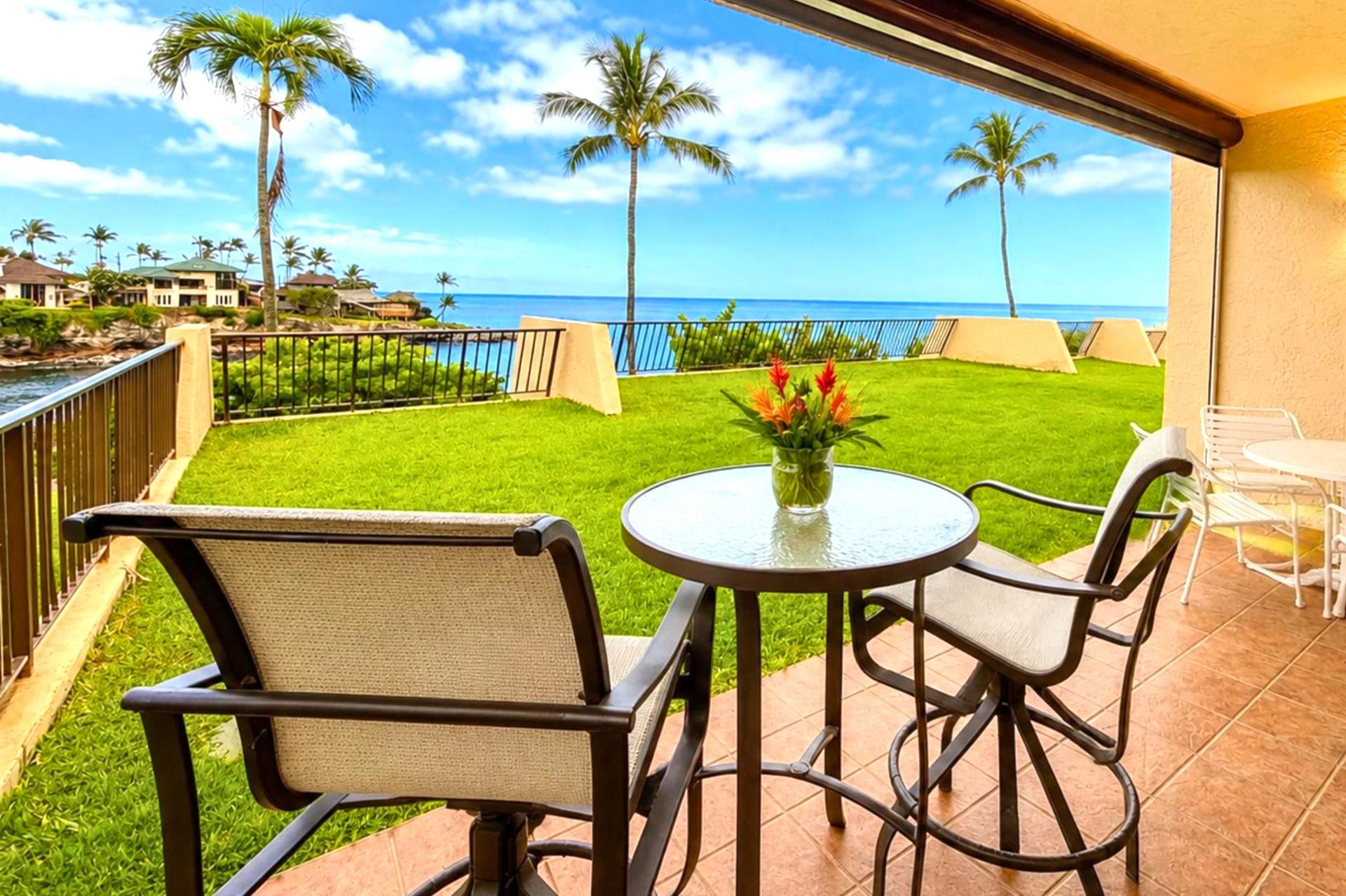 Eine Terrasse mit Tisch und Stühlen, ein kleiner Garten und Blick auf das Meer.