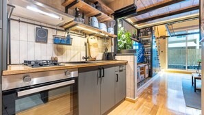 Eine moderne Küche mit Holzschränken, einem eingebauten Backofen und einem großen Fenster mit Blick auf einen Balkon.