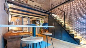 Ein modernes Interieur mit Bar, Ledersitzmöbeln und einer Wendeltreppe an einer Ziegelwand.