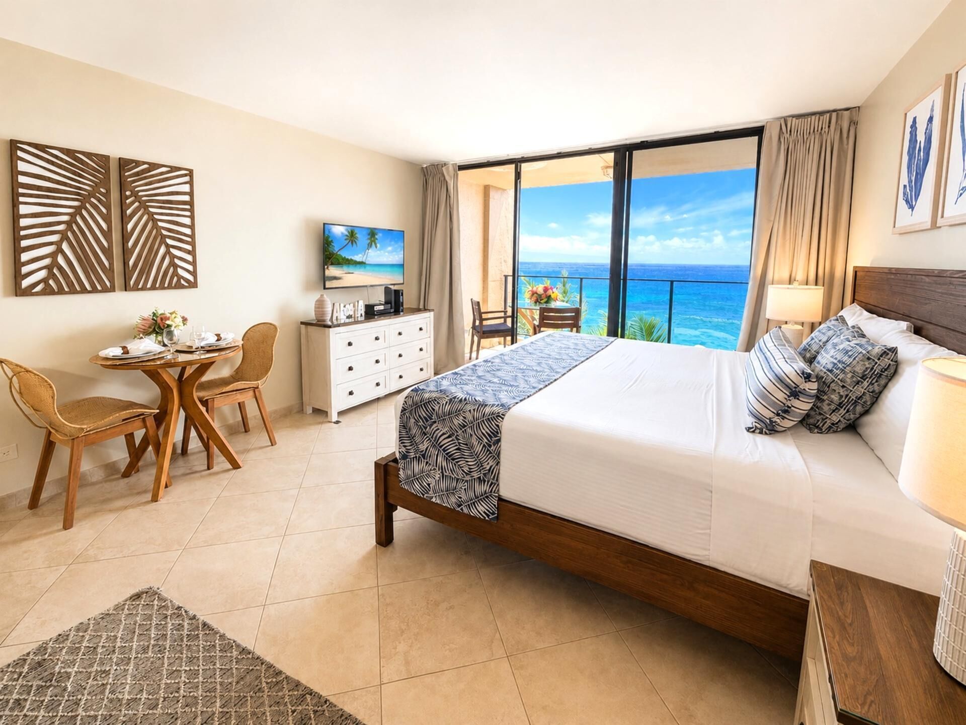 Ein Hotelzimmer mit Bett, Schreibtisch, Stuhl, Fernseher und einem Balkon mit Meerblick.