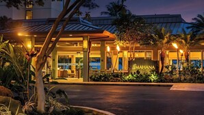 A hotel entrance with a sign reading 'MAHANA,' surrounded by tropical plants and palm trees. - Mahana Villas | Oceanfront 3 BR Sleeps 10 | Car Incl. w/ 6+ Nights | MAH ML-4160 by KBM (Lahaina)