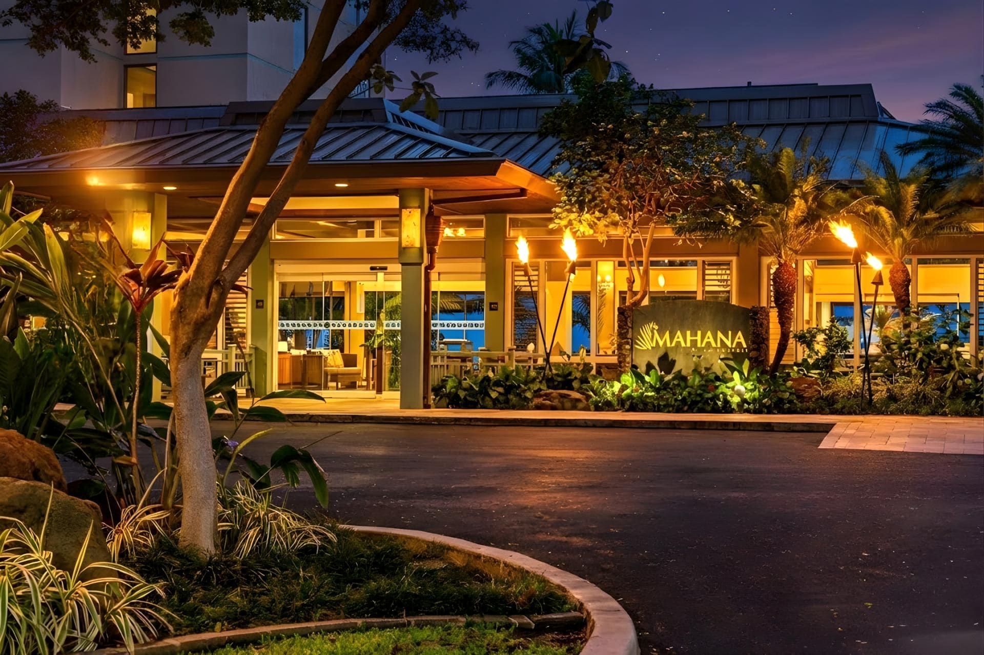 A hotel entrance with a sign reading "MAHANA" and a well-lit driveway.