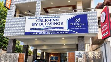 A hotel with a signboard advertising luxury rooms, contact details, and a logo.
