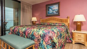 Ein Zimmer mit einem Bett, einer Bank, einem Nachttisch, einem Gemälde und Blick durch eine Glastür.