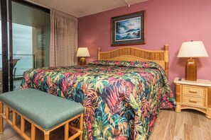 Ein Zimmer mit einem Bett, einer Bank, einem Nachttisch, einem Gemälde und Blick durch eine Glastür.