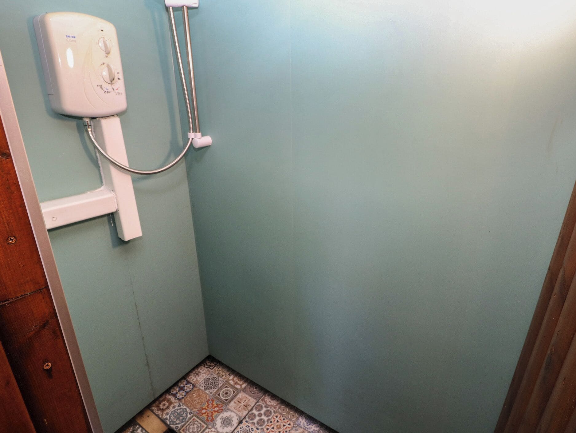 A bathroom with a toilet, shower, and patterned floor tiles.
