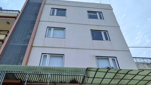 A multi-story building with a flat facade, large windows, and a covered entrance area. - Kashika Inn and Comfort Stays (Varanasi)
