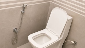 A modern bathroom with a toilet, a shower, and a tiled wall. - Kashika Inn and Comfort Stays (Varanasi)