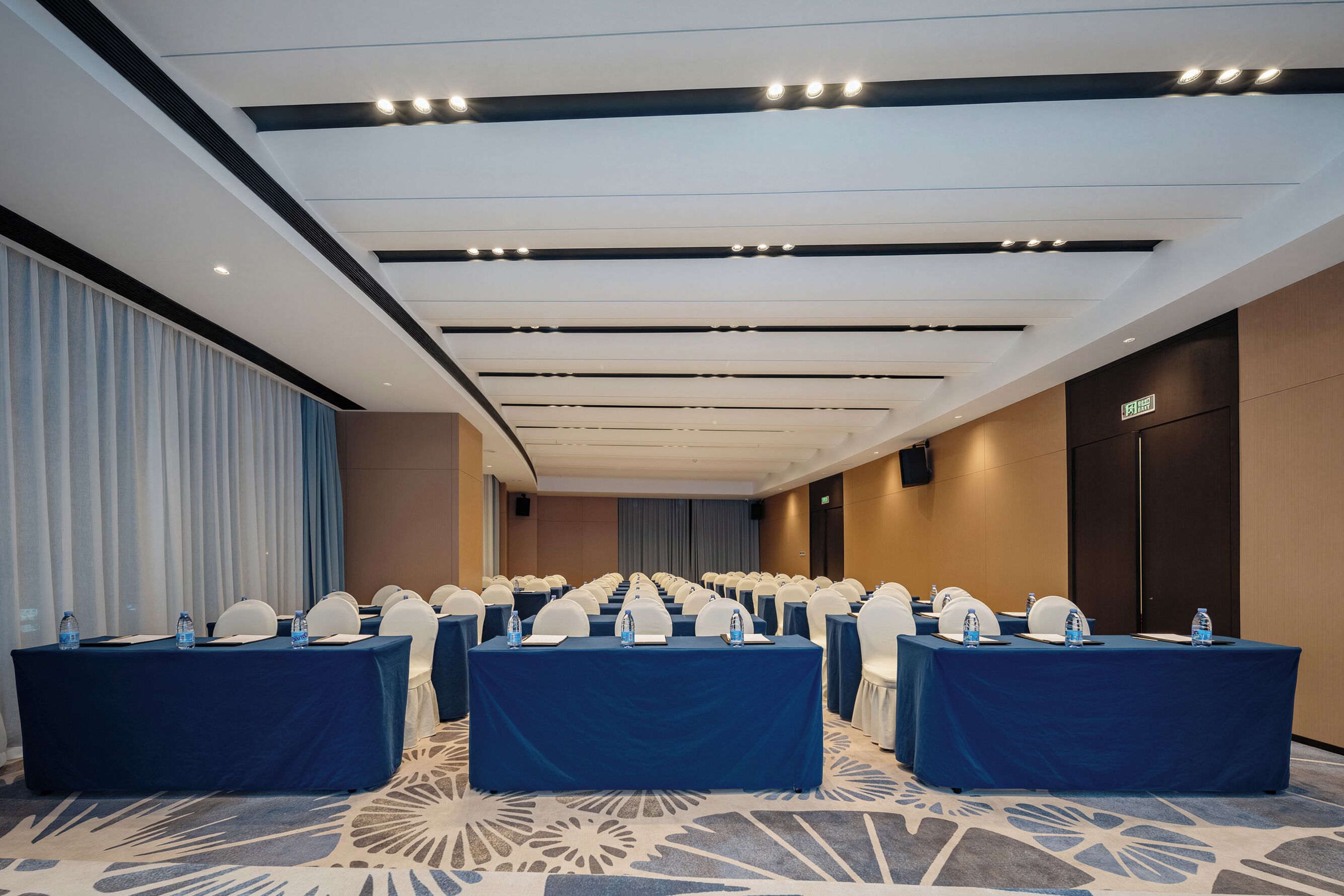 A conference room with rows of tables, chairs, and water bottles.