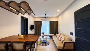 A modern living room with a sofa, a dining table, and a TV. - Calangute Heights (Calangute)