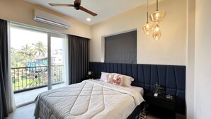A bedroom with a bed, a ceiling fan, an air conditioning unit, a nightstand, and a view of the outside. - Calangute Heights (Calangute)