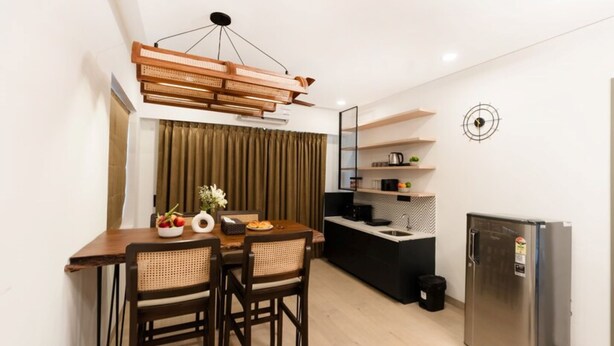 A compact kitchen with a dining area, a modern refrigerator, and a ceiling light fixture. - Calangute Heights (Calangute)