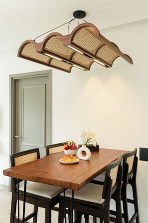 Un comedor con una mesa de madera, sillas y una lámpara original de fibra.