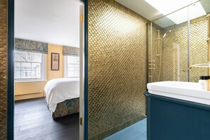 A room with a bed, a bathroom with a sink and mirror, and a textured wall. - Modern Classic in Angel, by Veeve (London)