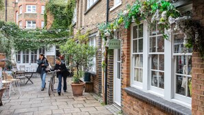 Une ruelle étroite pavée de briques, avec un café appelé « Perks », des tables à l’extérieur et un vélo.