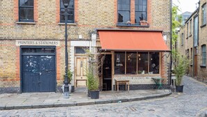 Un bâtiment en briques avec une enseigne indiquant « Imprimeurs et papetiers » et une devanture ornée d’un auvent rouge.