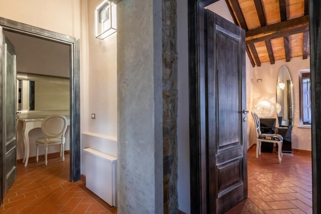 A hallway with a stone pillar, a wooden door, and a chair.