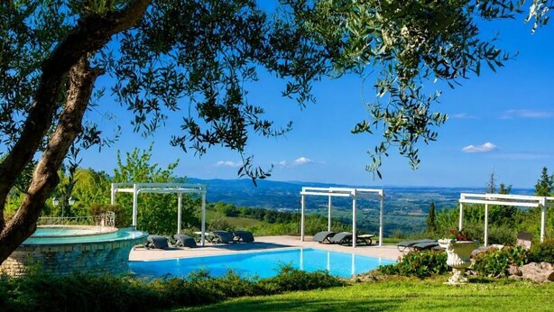 Piscina com vista para a paisagem, rodeada por vegetação e uma estrutura de pérgula.
