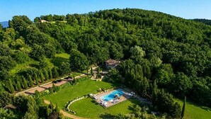 Vista aérea de uma propriedade com piscina, uma casa e vegetação ao redor.