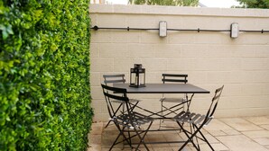 A patio with a table and chairs, a lantern, and a white wall with electrical outlets. - Guestready - Camden Studios (London)