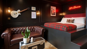 A room with a bed, a couch, a guitar, framed certificates, and a neon sign. - Guestready - Camden Studios (London)