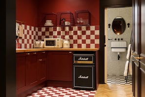 A kitchen with checkered tiles, a microwave, a coffee maker, and a Marshall amplifier.