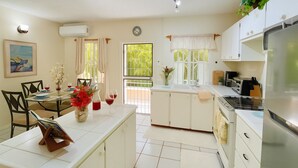 Een keuken met een eettafel, stoelen, een koelkast en een raam met gordijnen.