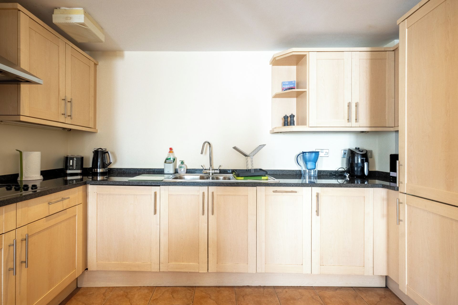 A kitchen with wooden cabinets, a sink, a coffee maker, and a kettle.