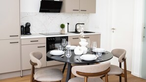 Une cuisine moderne avec une table à manger pour quatre personnes, un four encastré et une hotte noire.