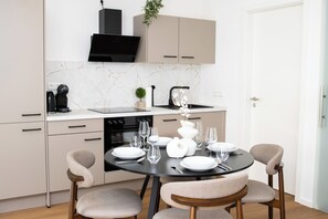 Eine moderne Küche mit Esstisch für vier Personen, einem eingebauten Backofen und einer schwarzen Dunstabzugshaube.