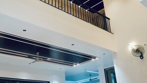 Amplia sala de estar con techo alto, un balcón y un diseño moderno.