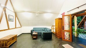 Een kamer met een houten plafond, een blauwe bank, een kleine tafel en een kast.