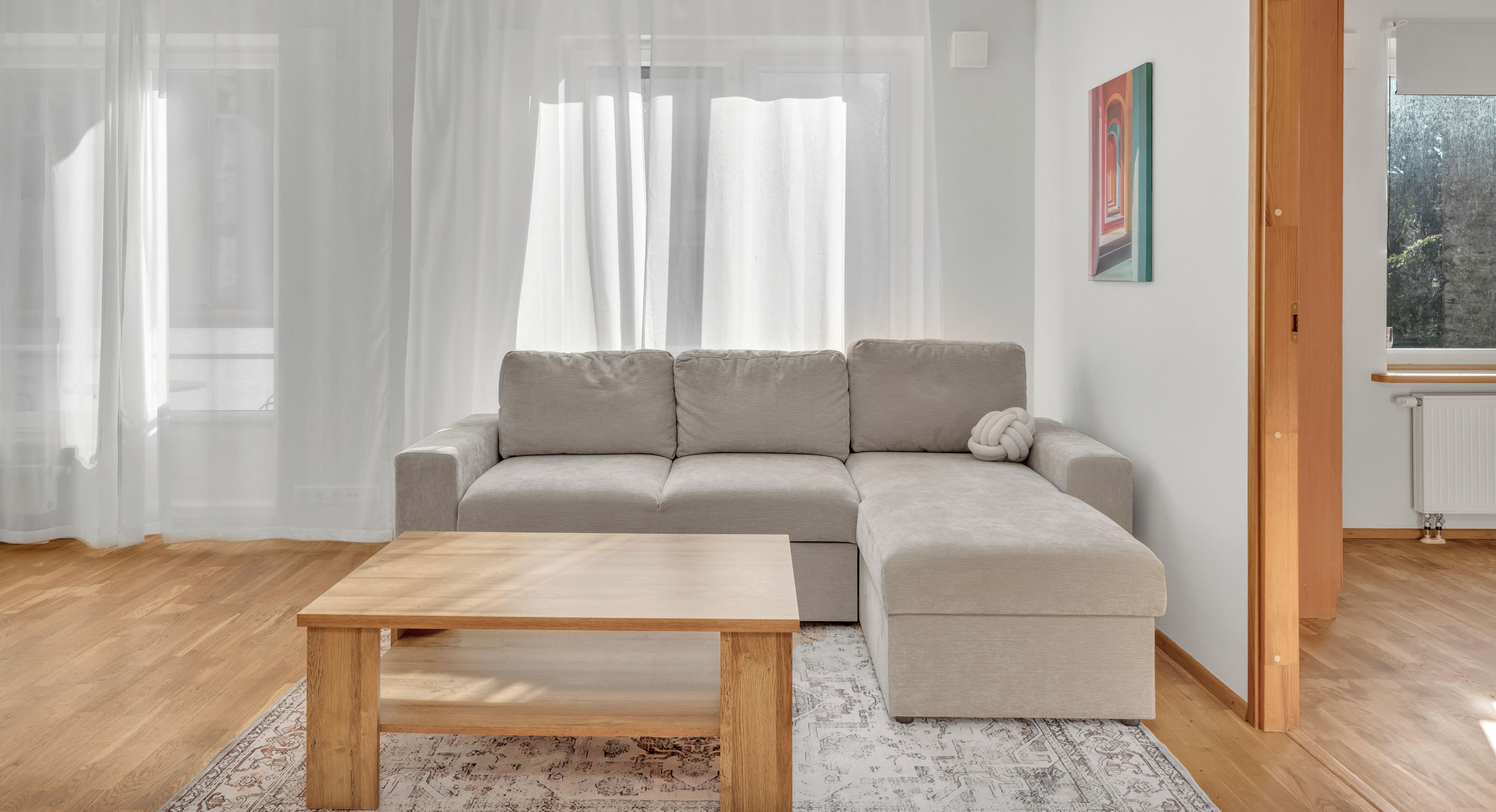 Un salon moderne avec un canapé de couleur claire, une table basse en bois et un tapis à motifs.