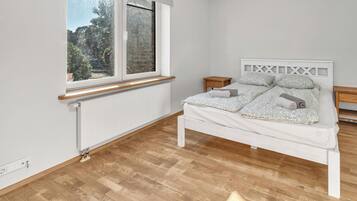 A bedroom with a bed, a window, a radiator, and a wooden floor.